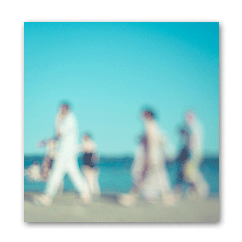 Mehrere unscharfe Silhouetten von Menschen laufen am Strand entlang.
