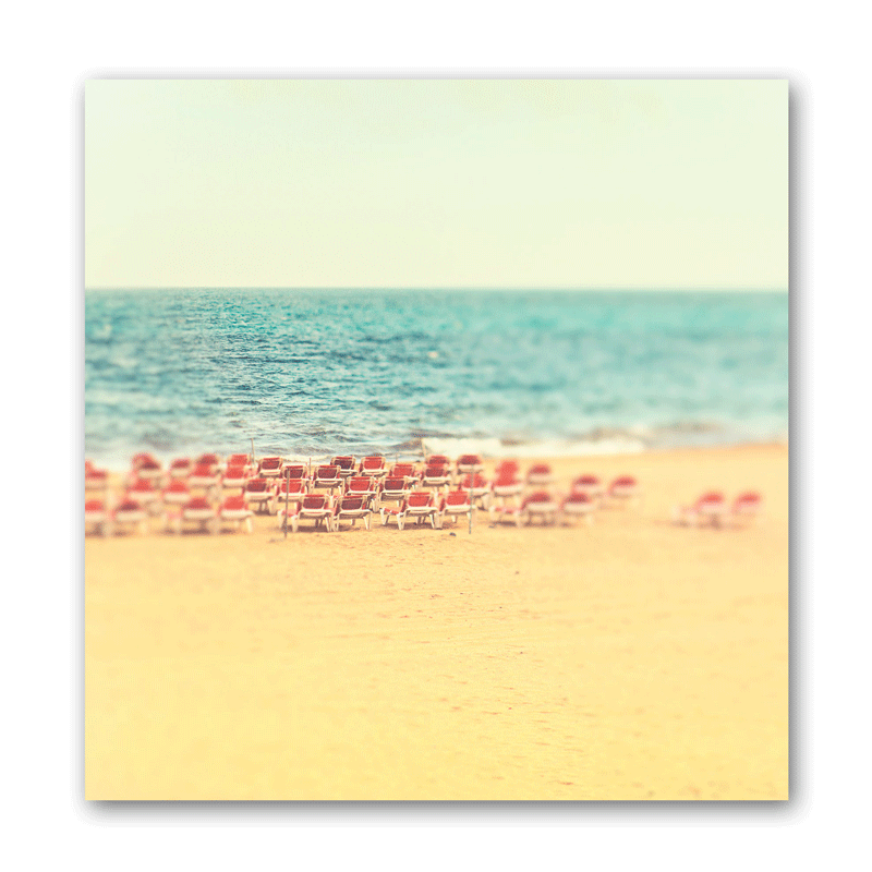Stühle stehen am Strand aufgereiht wie in einem Theater.