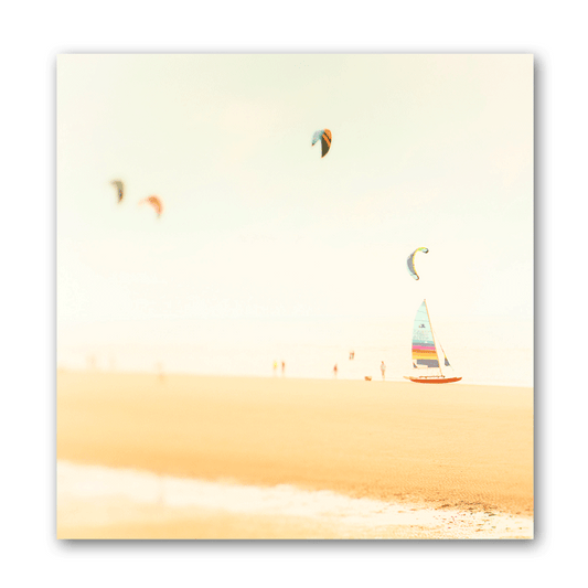 Ein kleines Segelboot steht am Strand neben Kitesurfern.